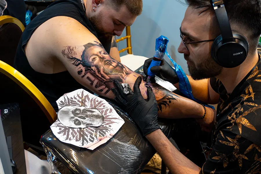 Tattoo artist tattooing a male arm