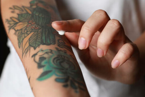 Woman applying cream on her arm with tattoos