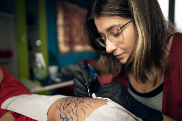 Focused female tattoo artist tattooing the customer