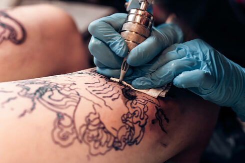 Closeup artist fill circuit tattoo in a professional salon