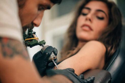 Tattoo artist creating a tattoo on a girl's arm