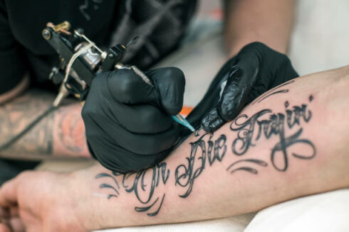 Tattoo artist tattooing a male model.